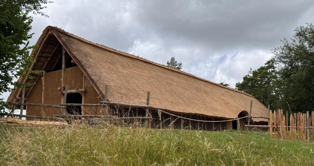 Vue global de la halle du néolithique avec façade torchis et toiture en chaume